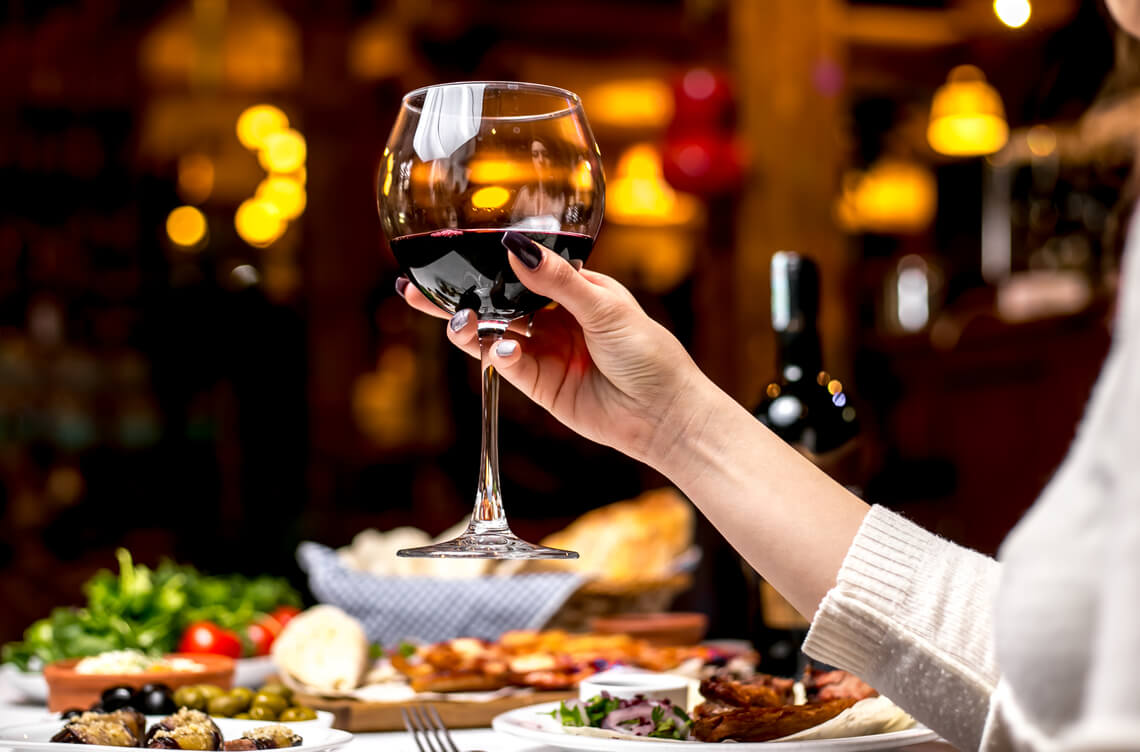 mulher segurando uma taça de vinho tinto, adega covabra