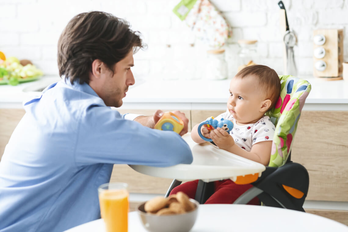 Pai olhando para o bebê na cadeira de alimentação de acordo com a rotina do bebê