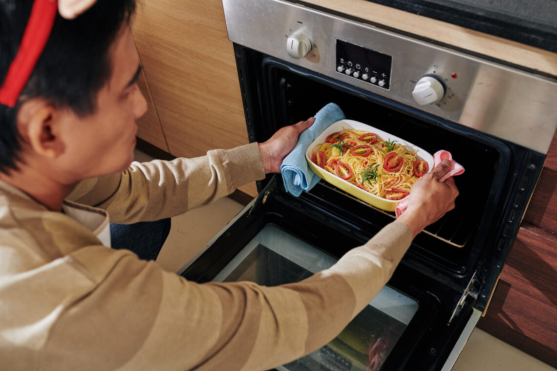 homem segurando uma travessa de macarrão de forno