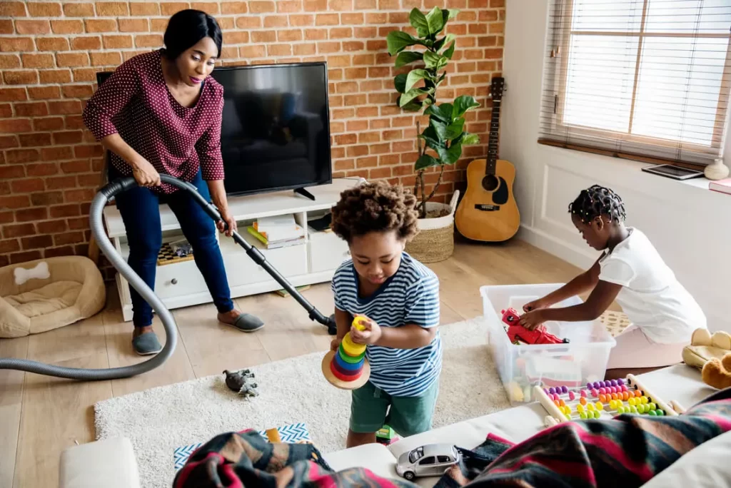 Mãe negra e filhos fazendo a limpeza da casa