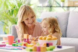 Mãe e filha ainda nova se divertindo com brinquedos na sala