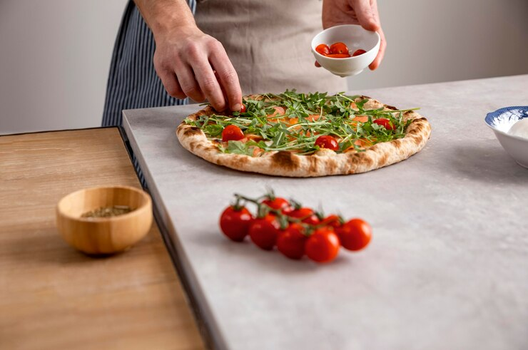 Homem colocando os últimos ingredientes para terminar de fazer sua pizza em casa