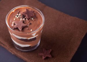 Mousse de chocolate em um copinho, enfeitado com confetes de estrelinhas.