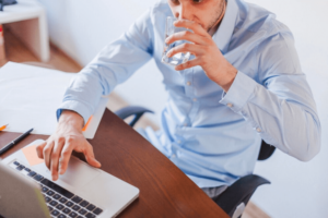 Homem tomando água em meio ao expediente do escritório
