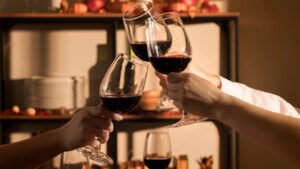três taças de vinhos sendo brindadas em um jantar de outono.