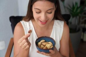 Mulher comendo castanhas do Pará, uma espécie de oleaginosa.