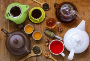 Chaleiras, xícaras, ervas, chás espalhados em uma mesa visto de cima. 