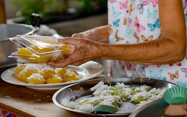 Mulher preparando comidas típicas em sua cozinha.