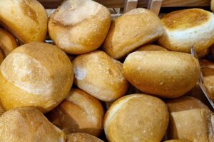 Vista superior de uma cesta cheia de pão francês bola bem dourados. Os pães possuem formato arredondado, casca crocante e lisa, ideais para serem utilizados como uma variação crocante de pão para hambúrguer artesanal.