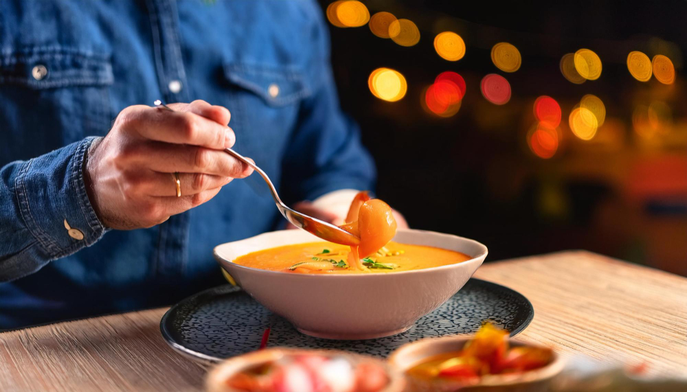 Uma pessoa servindo sopa em uma tigela.